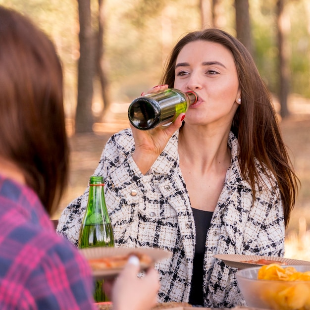 Donna che beve birra mentre all'aperto con gli amici