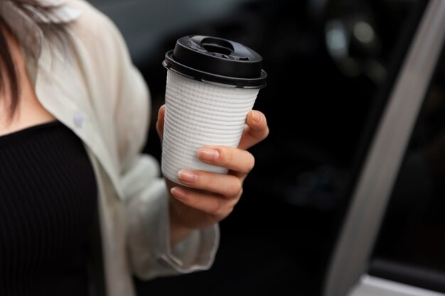 Donna che beve una tazza di caffè con la sua auto elettrica