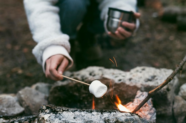 Donna che brucia marshmallow nel fuoco di campo