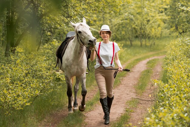 Donna che cammina con un cavallo in campagna