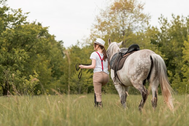 Donna che cammina con un cavallo in campagna