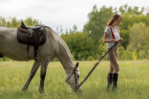 Donna che cammina con un cavallo in campagna