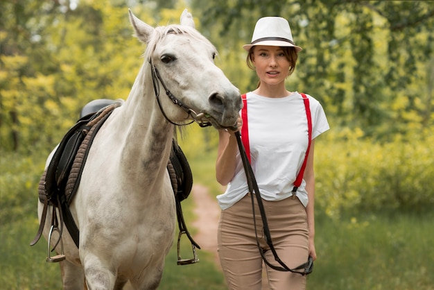 Donna che cammina con un cavallo in campagna