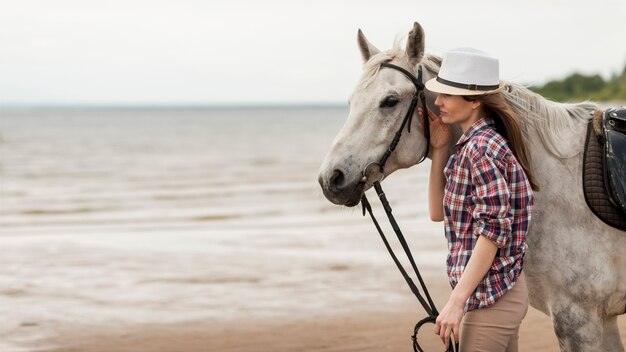 Donna che cammina con un cavallo sulla spiaggia