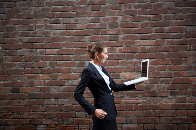 Donna che cammina con un computer portatile