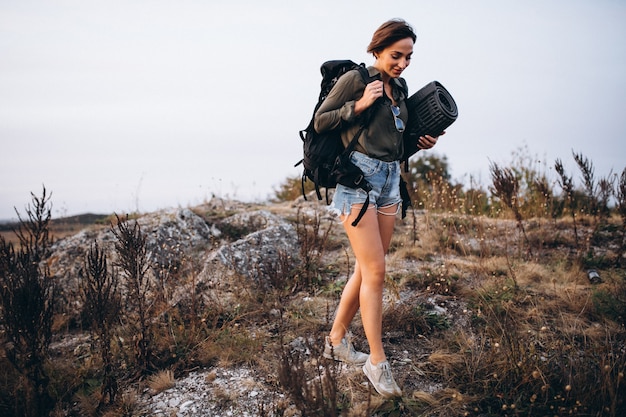 Donna che cammina in montagna con borsa da viaggio