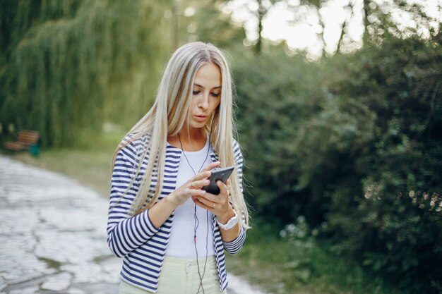 Donna che cammina in un parco con un cellulare