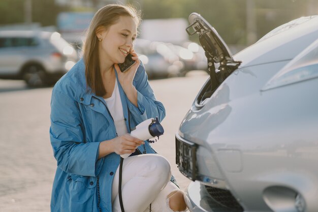 Donna che carica elettro automobile alla stazione di servizio elettrica