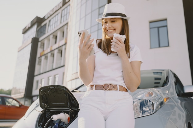 Donna che carica elettro automobile alla stazione di servizio elettrica