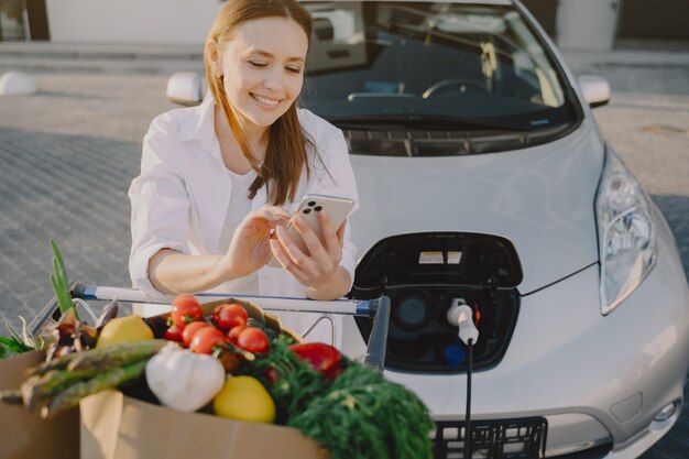 Donna che carica elettro automobile alla stazione di servizio elettrica