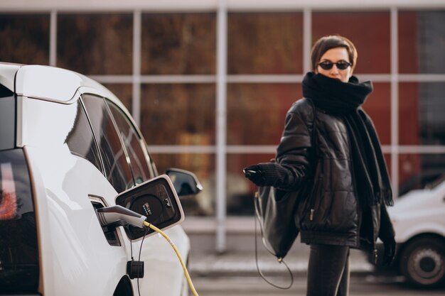 Donna che carica elettro automobile in strada