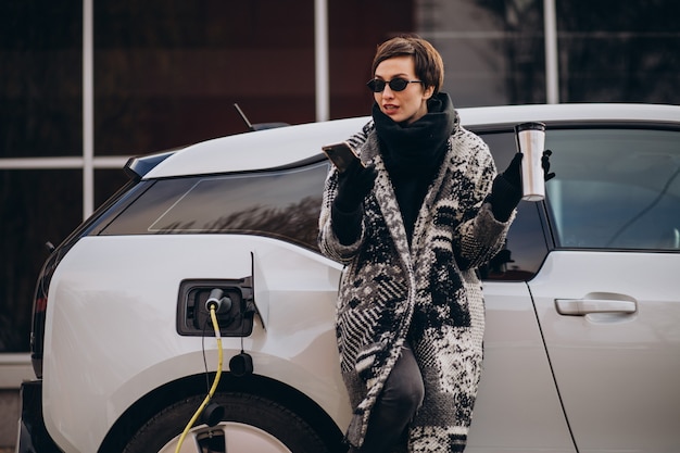 Donna che carica elettro automobile in strada