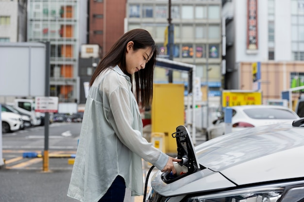 Donna che carica la sua auto elettrica alla stazione