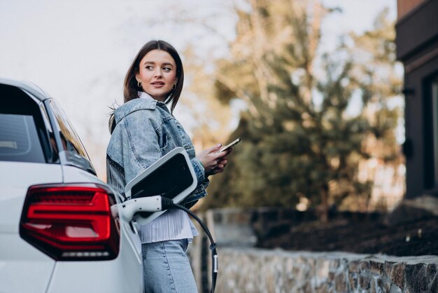 Donna che carica la sua auto elettrica con la pistola di ricarica