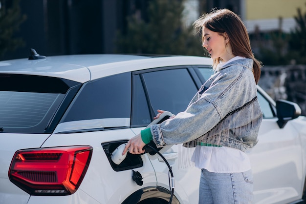 Donna che carica la sua auto elettrica con la pistola di ricarica