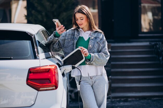 Donna che carica la sua auto elettrica con la pistola di ricarica