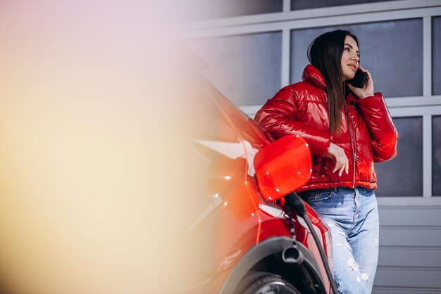 Donna che carica un'auto elettrica presso la stazione di ricarica