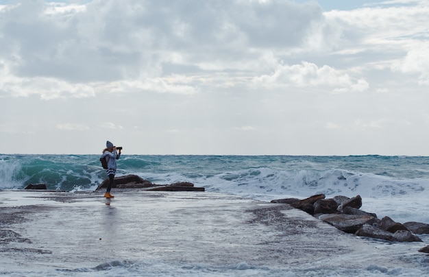 donna che cattura foto con la spiaggia di Cameron durante il giorno con il mare