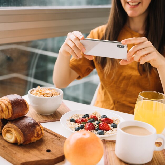 Donna che cattura maschera della prima colazione al tavolo