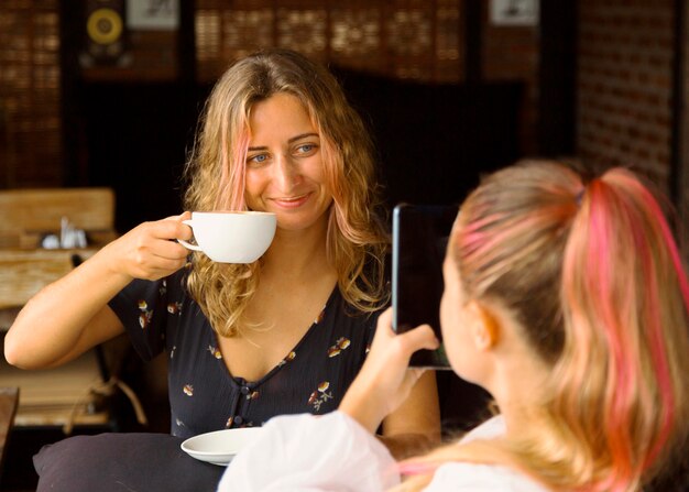 Donna che cattura maschera della sua amica mentre beve il caffè