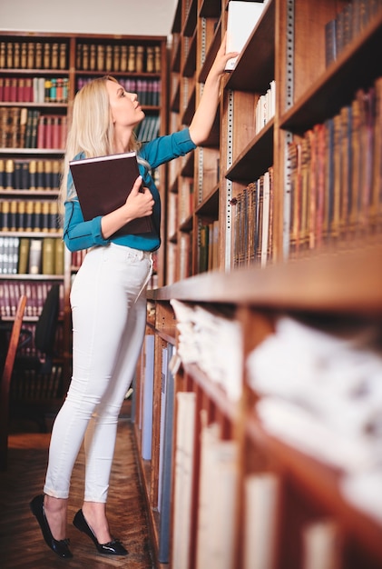 Donna che cerca un libro in biblioteca