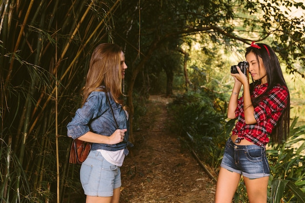 Donna che clicca la fotografia del suo amico con la macchina fotografica in foresta