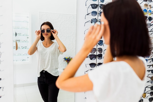 Donna che controlla gli occhiali da sole in specchio