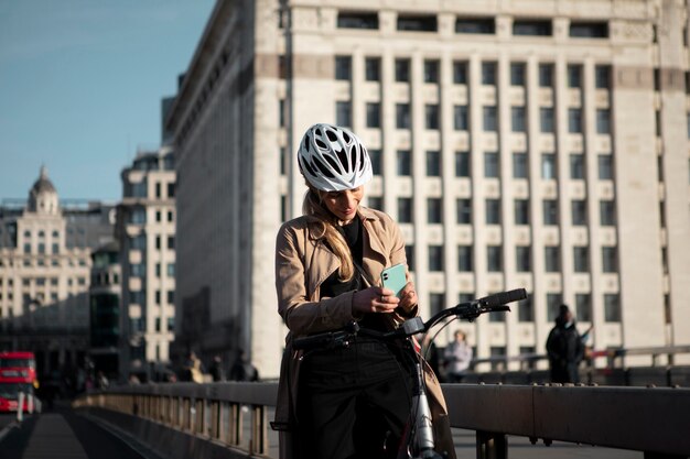 Donna che controlla il suo smartphone e si siede sulla sua bicicletta