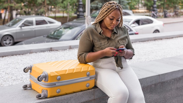 Donna che controlla il suo telefono accanto al suo bagaglio