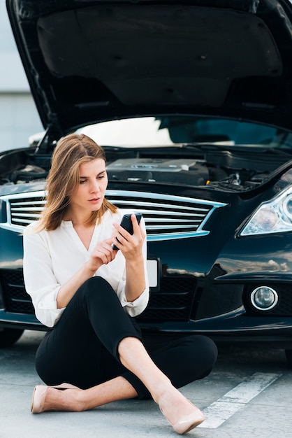 Donna che controlla il suo telefono e l'automobile nera