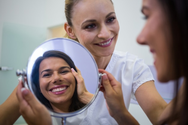 Donna che controlla la sua pelle allo specchio dopo aver ricevuto un trattamento cosmetico