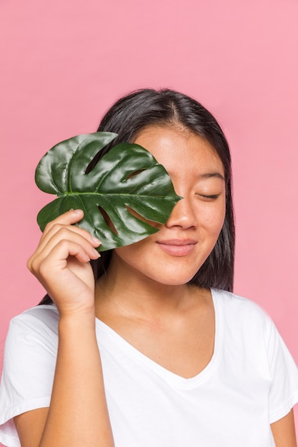 Donna che copre il suo occhio con foglia di monstera