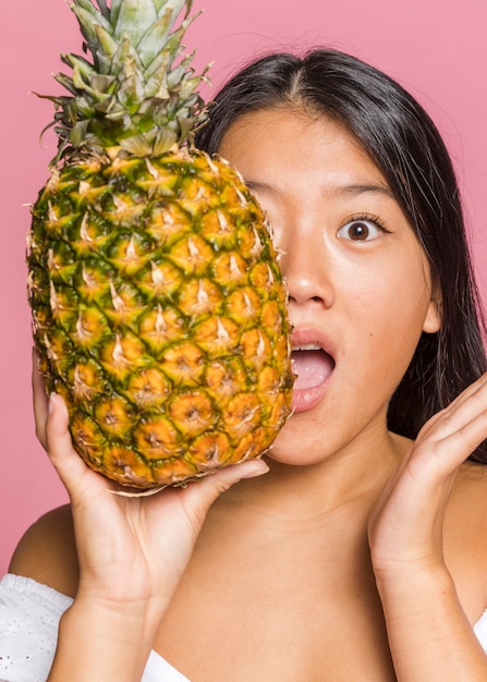 Donna che copre il viso con ananas a grandezza naturale