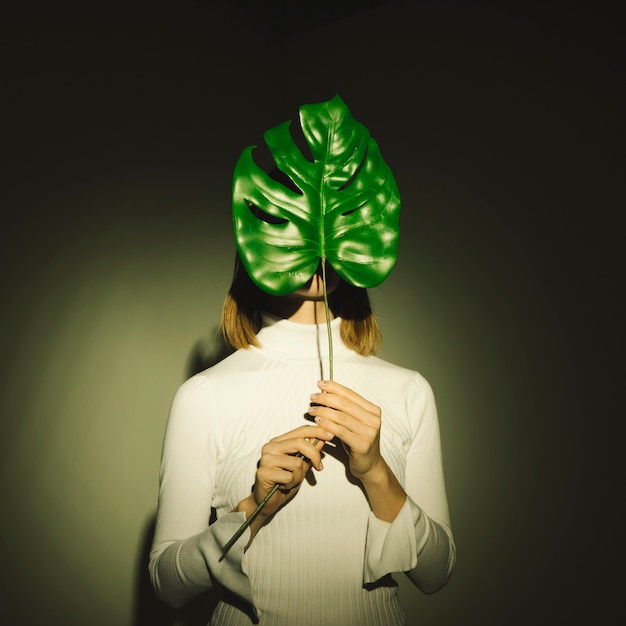 Donna che copre il viso con foglia verde