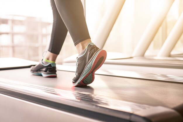 Donna che corre in una palestra su un concetto di tapis roulant per l'esercizio, la forma fisica e lo stile di vita sano