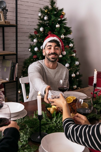 Donna che dà regalo ad un amico a cena di Natale