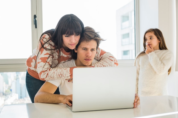 Donna che dà supporto a suo marito che lavora al computer portatile a casa