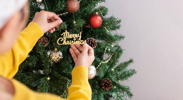 Donna che decora un albero di Natale con ornamenti nel giorno di Natale.