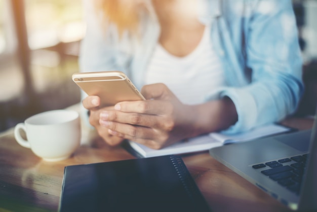 Donna che digita sul suo telefono cellulare con una tazza