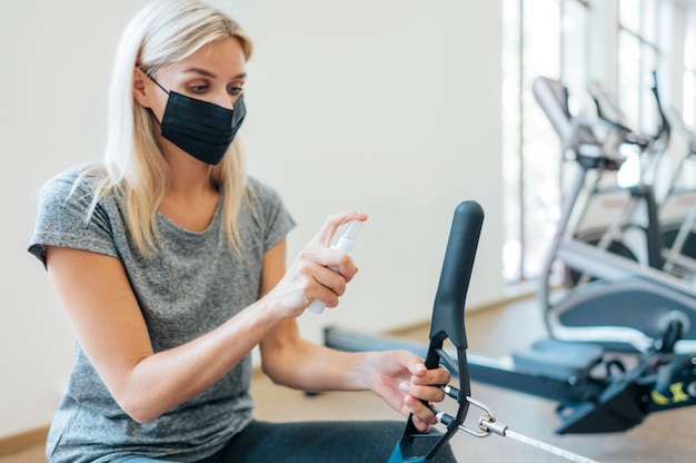 Donna che disinfetta attrezzature da palestra durante una pandemia