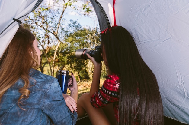 Donna che esamina il suo amico che prende fotografia in tenda