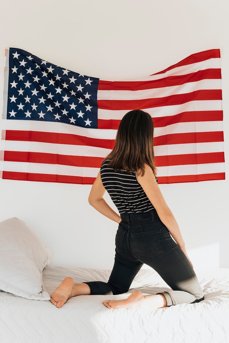 Foto gratuito donna che esamina la bandiera degli stati uniti sulla parete che sta sul letto