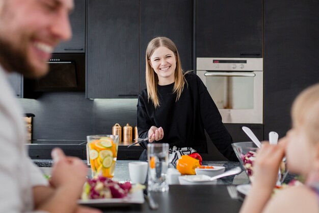 Donna che esamina la famiglia che mangia insalata