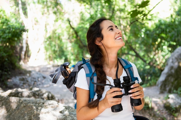 Donna che esplora e ammira la natura mentre usa il binocolo