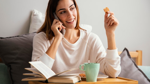 Donna che fa colazione e parla al telefono a casa