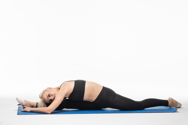 Donna che fa esercizi di stretching sul pavimento in studio su bianco