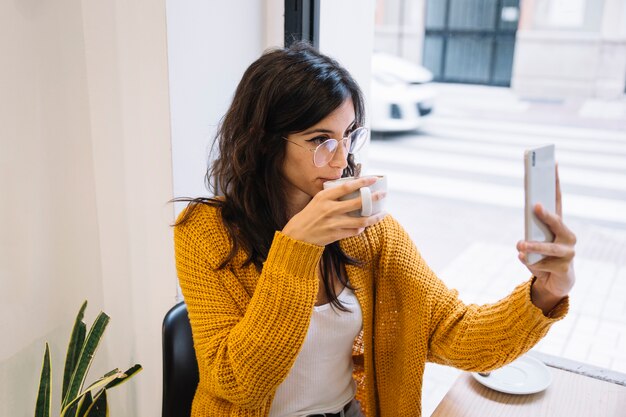 Donna che fa foto di se stessa nella caffetteria