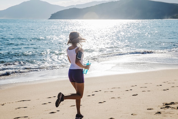 Donna che fa jogging con la bottiglia di acqua