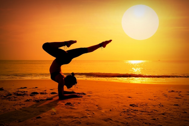 Donna che fa pino sulla spiaggia al tramonto