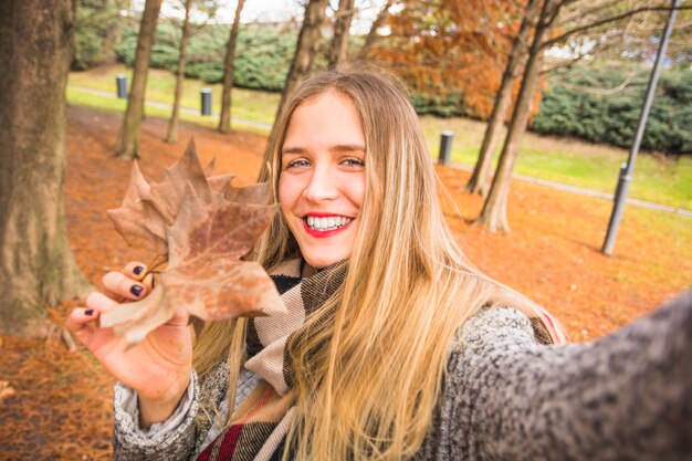 Donna che fa selfie con congedo d&#39;autunno